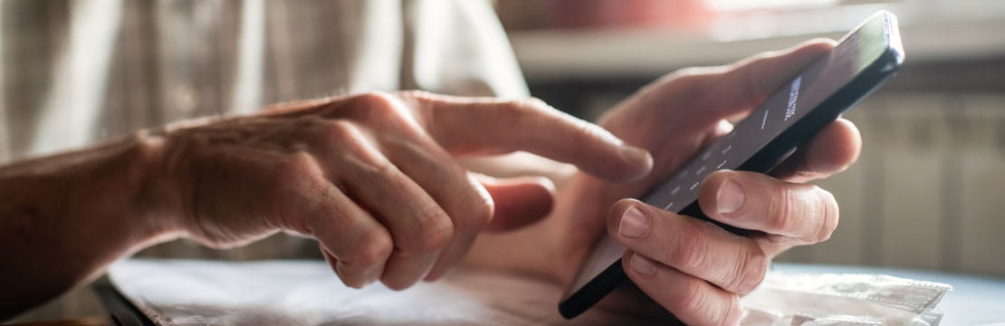 Person using a smartphone while seated at a table.
